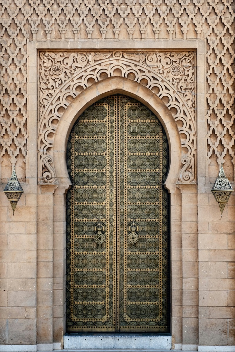 Monumental engraved brass door within a carved stone arch, Rabat