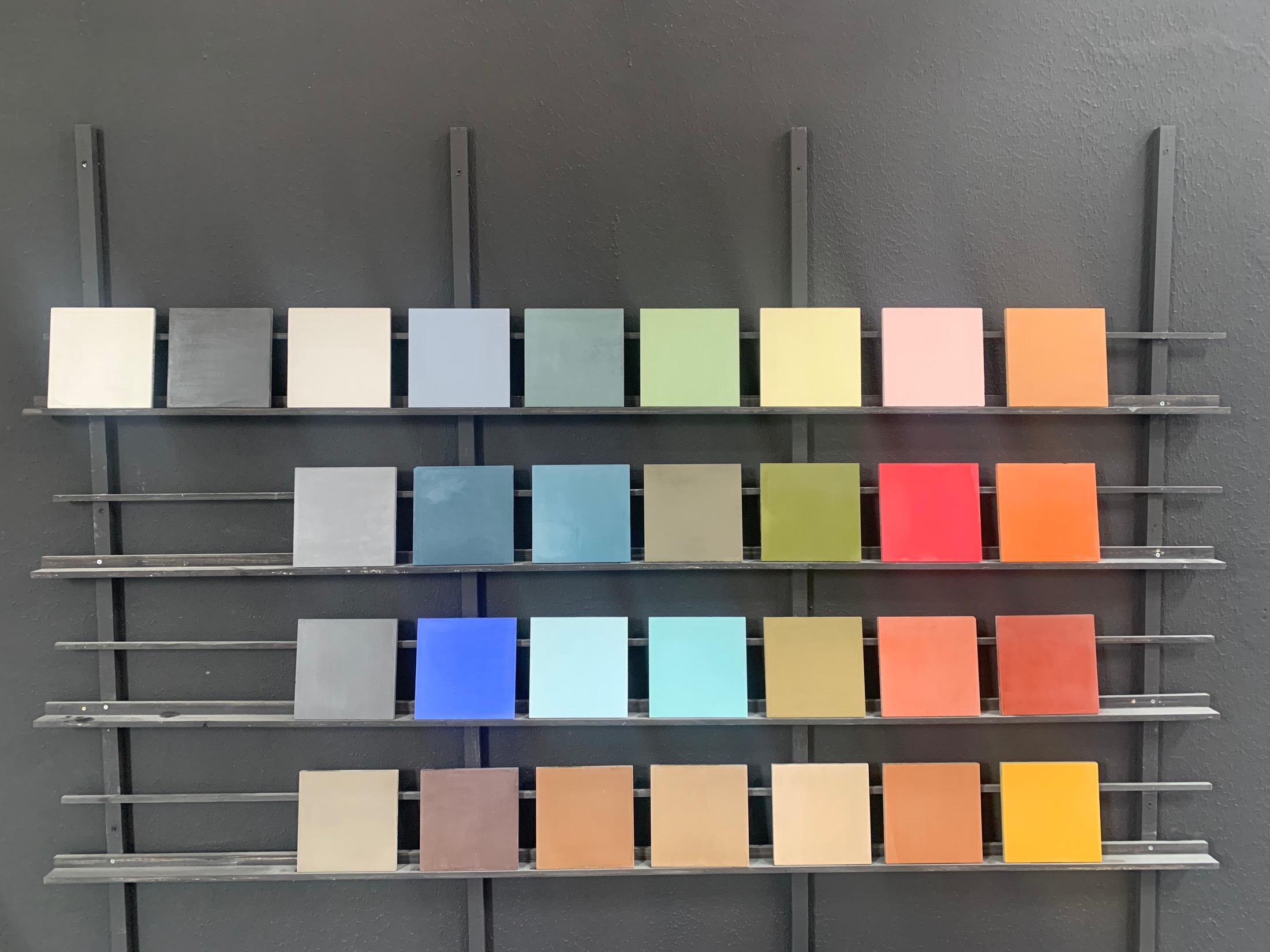 The full Zeljora cement palette mounted on metal display rails against a dark wall in the Casablanca workshop