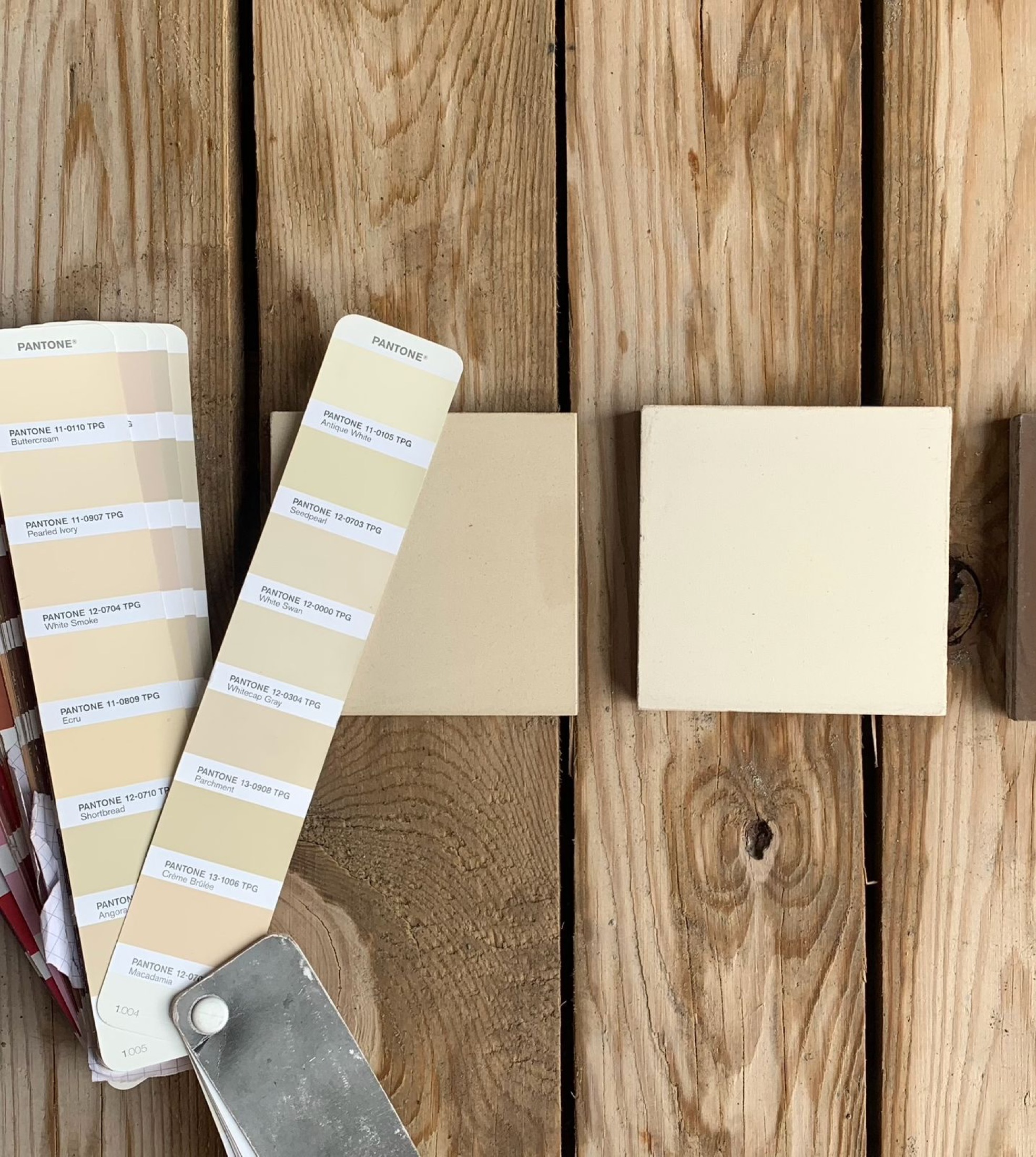 Pantone color cards beside cement tile samples on a wooden surface