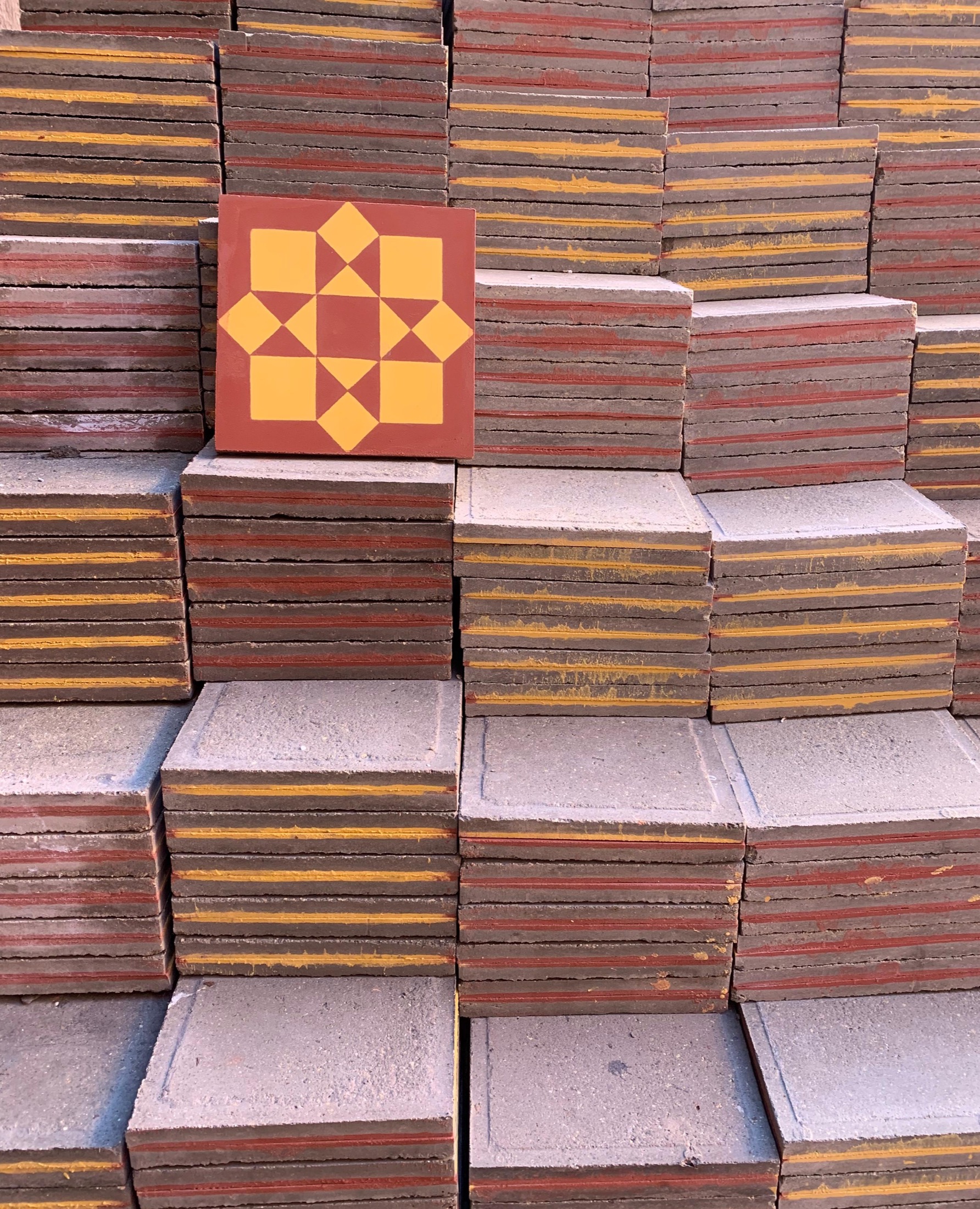 Stacked pigmented cement tiles in the Zeljora production yard, star-pattern tile on top
